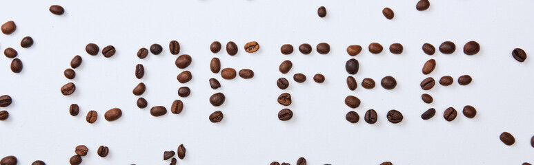 panoramic shot of of coffee lettering made of beans on white background