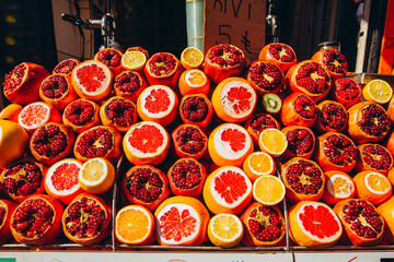 Orange, grapefruit, pomegranate sliced. fruit background. Ripe juicy pomegranates, tangerines and oranges are sold on the counter of a fruit shop on Istanbul street.