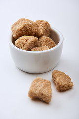 close up view of granulated brown sugar in bowl on white background