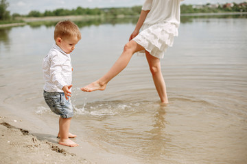 Family walking near water. Mother in a white dress. Cute little boy