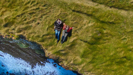 Fototapeta premium Two girls lying in the grass at the cliffs of the Irish coast - drone view from above - travel photography
