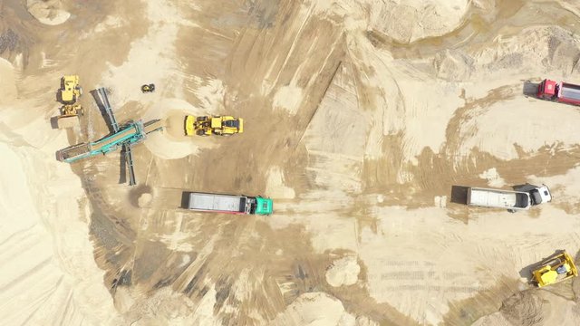 Aerial view loading bulldozer in open air quarry. Sand mining industry. Bulldozer machine. Crawler bulldozer moving at sand mine. Mining machinery working at sand quarry. Drone view of mining equipmen