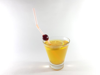 Drink with fruit in a transparent glass. Lemon and cherry for a snack. Yellow liquid in a glass. Photo