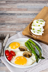 Breakfast. Scrambled eggs, asparagus, champignons, cherry tomatoes, sandwich