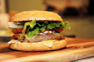 Closeup of home made beef burger with lettuce and mayonnaise served on little wooden cutting board.
