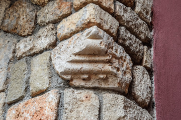 Stone in the wall inserted from a destroyed other building. Stone with carved patterns on it.
