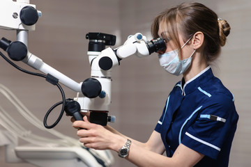 Doctor making teeth examination research survey using microscope in dentistry. Dentist is treating patient in modern dental office.