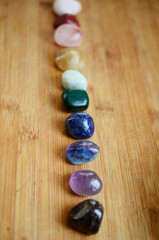 Rainbow Healing Crystals on wood table. Natural lighting with macro lens, rainbow stones. Clear Quartz, Pink Calcite, Jasper, Calcite, Malachite, Green Quartz, Fluorite, Sodalite, Amethyst, Onyx