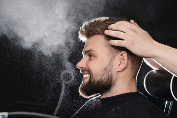 Professional hairdresser barber using talcum powder for his client hair sitting in a barber chair...