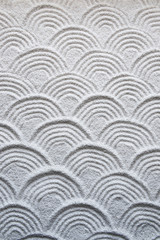 Background of graphic wave patterns raked into the white sand of a Japanese Zen garden
