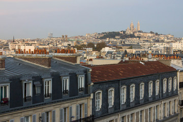 Obraz premium Amazing picturesque view of rooftops of Paris and beautiful facades of residential buildings on the streets of France. View of the large hill Montmartre and Basilica of the Sacred Heart of Paris above
