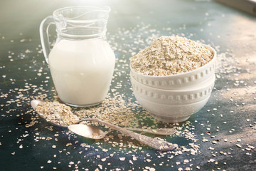 Raw Oatmeal in a bowl on the table, milk in a jug and spoons. Ingredients for Breakfast. The concept of healthy eating