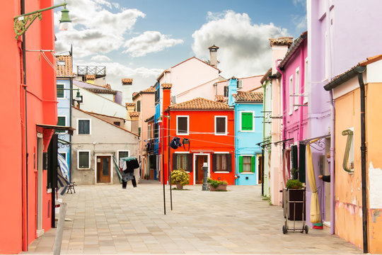 Bright street with colorful multi colored painted buildings. Sunny day and stylish facades of redifential buildings. Traditional architecture. Tiled brown roof and shutter windows. Drying linen, rope.