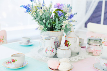 Obraz na płótnie Canvas Flowers, tea set and sweets on the table