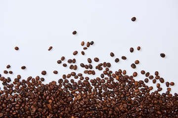 top view of scattered brown roasted beans on white background