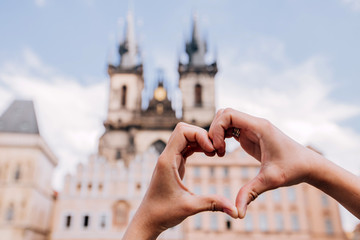 Girl showing heart shape love symbol over cityscape, Tyn Church. Woman making heart shape with...