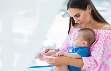 young mother sits by the window with her little son