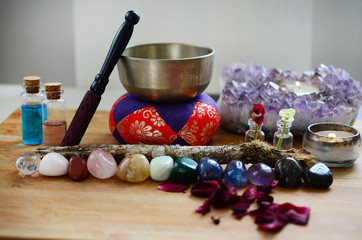 Healing crystals, fresh herbs, and tibetan singing bowl. Rainbow crystals on wood table, candles,...