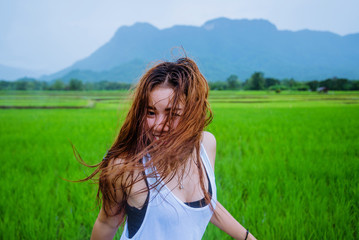 Asian women travel relax in the holiday.The girl smiled happy and enjoyed the rain that was falling. travelling in countrysde, Green rice fields, Travel Thailand.