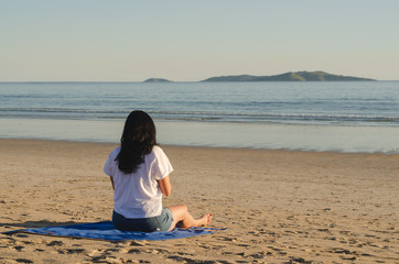 Fototapeta na wymiar Woman sitting looking at the sea in A Lanzada beach, O Grove, Galicia, Spain.