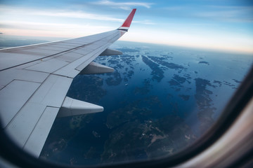 aircraft wing in the sunset light. Airplane wing against the blue sky from the porthole. view from the airplane porthole to the clouds.