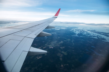Obraz premium aircraft wing in the sunset light. Airplane wing against the blue sky from the porthole. view from the airplane porthole to the clouds.