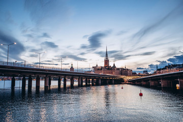 Scenic summer panorama of the Old Town (Gamla Stan) architecture in Stockholm, Sweden. view from Monteliusvagen hill on island Riddarholm and tower of church. Lake Malaren with blue sky, white clouds.