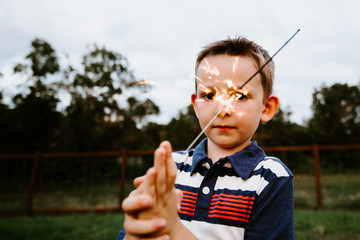 Happy boy playing with sparkler fireworks 