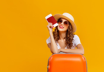 concept of travel. happy woman girl with suitcase and  passport on  yellow background.
