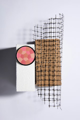 Cosmetics on different platforms like cardbox, styrofoam and a plastic net. Abstract conception.