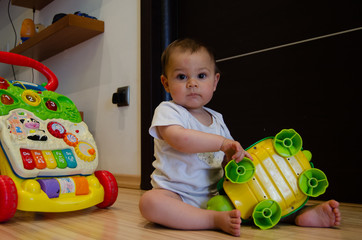 cute seven months old baby boy playing with educational toys on the floor