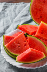 Cut slices of juicy watermelon on white plate on wooden table background
