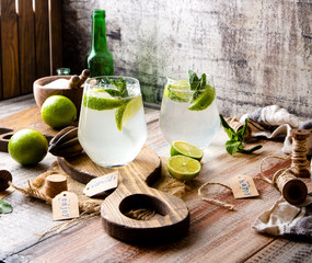 Two glasses of cold icy summer cocktail mojito with mint leaves and slices of lime