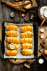 Overhead shot of delicious homemade baked sausages rolled in dough on baking tray on wooden rustic table