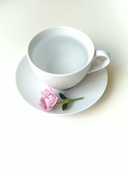 a small bouquet of light pink flower at the foot of a tea coffee Cup