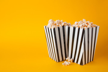 Popcorn in paper bag stand on yellow background side view