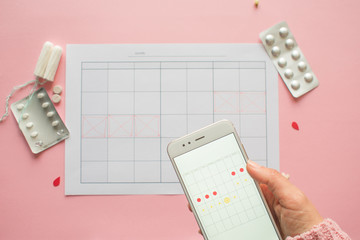 Menstrual cycle. Calendar for the month with marks and a mobile application on the smartphone...