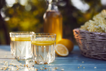 Two glasses of elderflower lemonade and bottle of homemade syrup