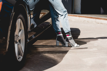 cropped view of fashionable young woman posing near car