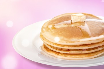 Stack of tasty pancakes with butter on a white plate