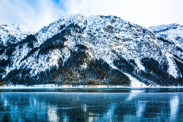 Beautiful winter landscape. Big mountains covered with snow and lake with bright blue water. 