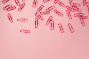 Scattered pink paper clips. Pink background. Flatlay.