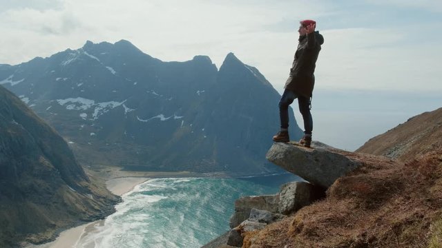 Hiker man with a standing on the edge of the mountain in Norway in with strong wind