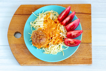 Pasta with tomato sauce and tomato on wooden table, top view.