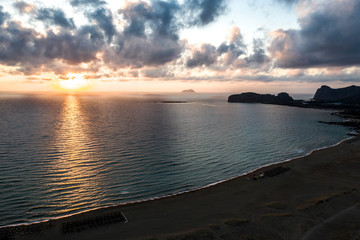 Brilliant clorful cloud filled sky as the sea wave rolls to the beach, Crete Falasarna Greece