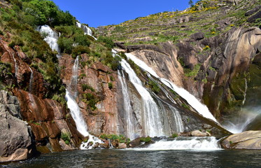 Colorful waterfall with rocks and vegetation. Ezaro, Spain.
