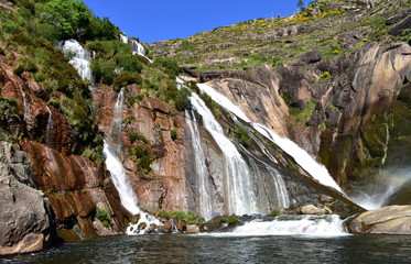 Obraz premium Colorful waterfall with rocks and vegetation. Ezaro, Spain.