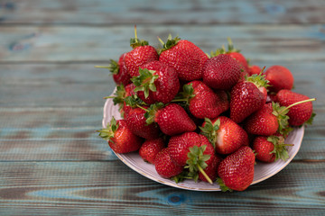 Ripe, freshly picked, red strawberry close-up shot on a white plate.