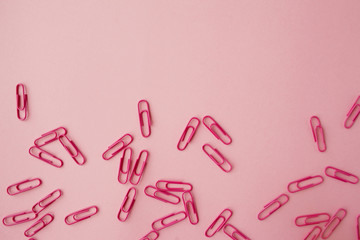 Scattered pink paper clips. Pink background. Flatlay.