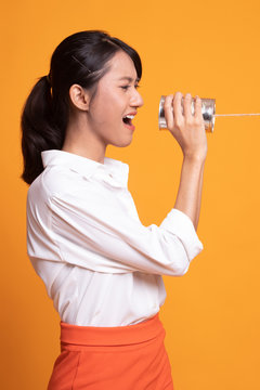 Young Asian woman shout with tin can phone.